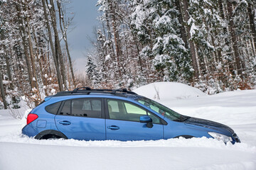 Car stuck in deep snow on cold winter day.