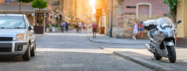 Close up of a motorcycle and a car parked on city street side.