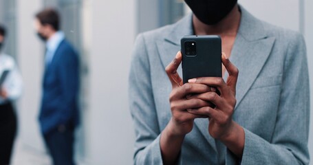 Everything looks great. Portrait view of the beautiful young multiracial woman using her smartphone while standing at the street and waiting her colleagues