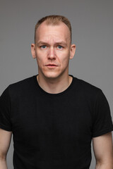 Obraz premium portrait of caucasian man in black t-shirt looks to the camera and smiles isolated on grey background