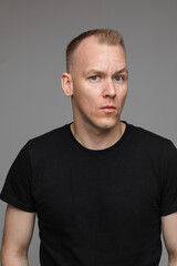 portrait of caucasian man in black t-shirt looks to the left isolated on grey background
