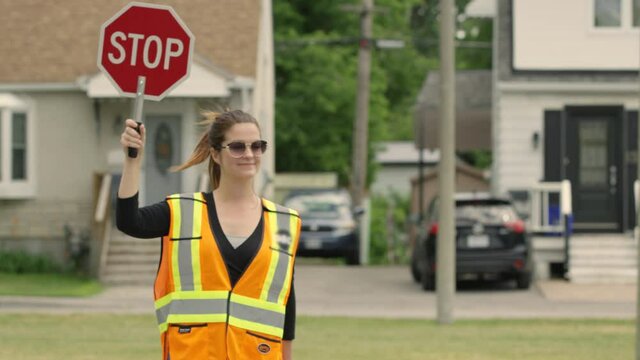Crossing guard walks out into the intersection holding up sign