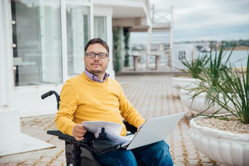 a man with disabilities in a wheelchair works at a computer on the Internet