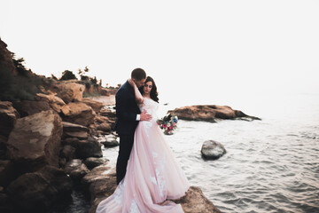 Happy and romantic scene of just married young wedding couple posing on beautiful beach