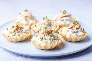 Tartlets stuffed with codfish liver, codfish caviar, cucumber and microgreens. Traditional cold portioned appetizer in a pastry basket. Close-up