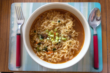 A bowl of instant Korean udon noodles with spicy soup, served in a bowl.
