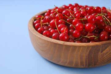 Fresh red currant in wooden bowl on dark table