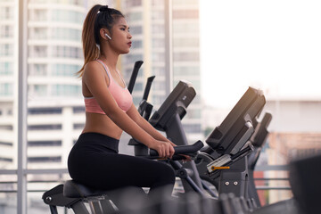 Cardio workout in gym by asian woman in a fitness gym , woman is using exercise bicycle indoor .