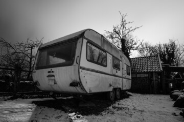 Naklejka na ściany i meble Old camping trailer standing at a farm at night in winter, Germany