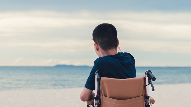 Back Of Disabled Child Looking To The Sea, Nature Background, Traveling For The Disabled By Wheelchair And Nature Therapy Concept.