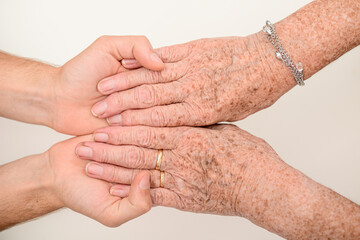 Fototapeta premium young person hands holding senior elderly people wrinkled hand close up
