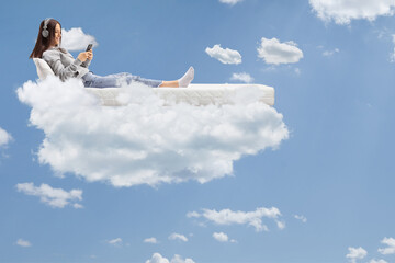 Female with headphones laying in a bed and floating in the sky