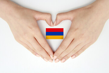 Women's hands create a heart inside the flag of Armenia on a white background.Background for...