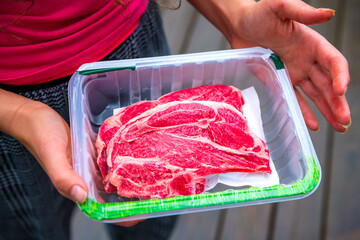 Red raw lamb meat shoulder chops from New Zealand packaged storebought with woman holding open plastic container showing © Andriy Blokhin