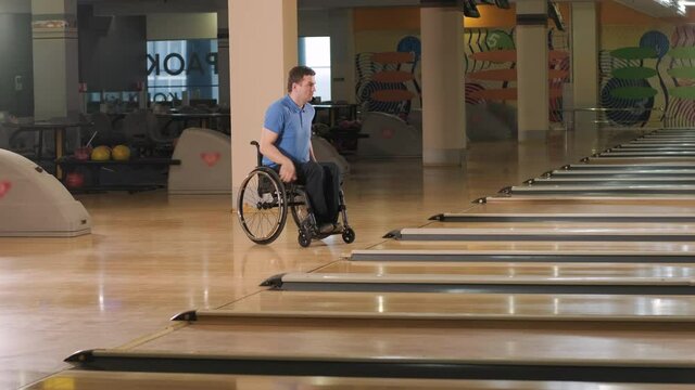 Two young disabled men in wheelchairs playing bowling in the club