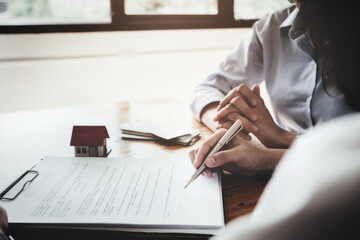 The customer holds a pen and reads the conditions in order to sign a house purchase contract with...