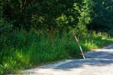 Dangerous concrete road in a rural area with holes and potholes on the side of the road. A pit on...