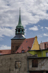 Fototapeta na wymiar CITYSCAPE - A church tower against the background of walls of old town houses 
