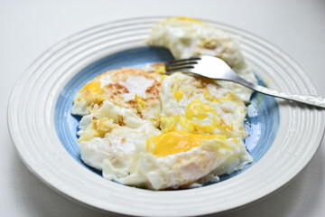 Fried eggs on a white plate with a fork