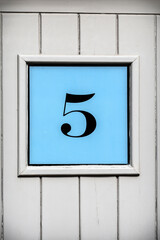 Number five framed on blue background on wooden door