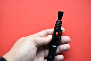 Brush for cleaning optics on a red background