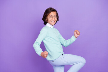 Profile photo of little nice brunet boy hands fists wear blue sweater spectacles isolated on purple...
