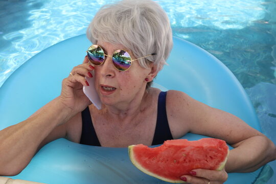 Surprised senior woman talking on the phone in swimming pool