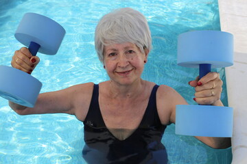 Senior woman holding dumbbells in swimming pool