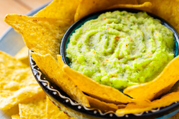Guacamole sauce and nacho chips. Tortilla chips and Mexican guacamole sauce in a bowl. Close-up