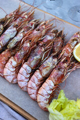Fish appetizers langoustines on a wooden table with white wine top view