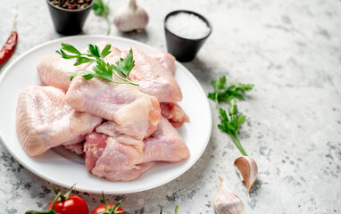 raw chicken wings on a white plate on a white stone background with copy space for your text