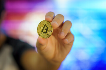 Bitcoin is the leading cryptocurrency in the financial world. Bitcoin logo on a golden coin held by...