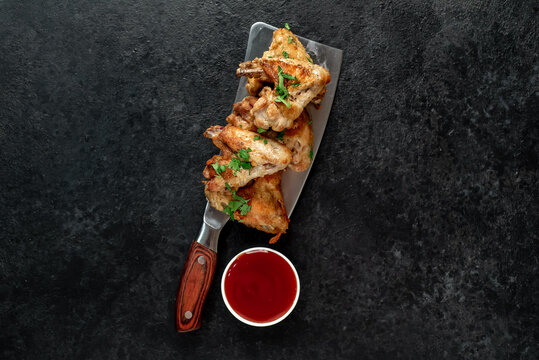 grilled chicken wings on a knife on a stone background