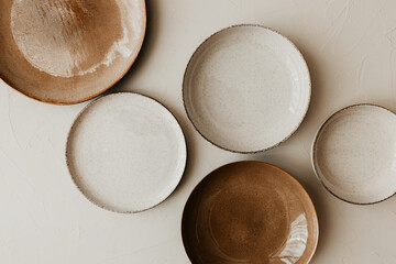 Five different size plate on beige background. Textured grainy pattern on the plates. Flat lay, top view. Brown and natural color plates.