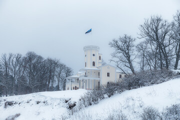 Fototapeta na wymiar Keila-Joa manor (Schloss Fall), neo-gothic style building of 19th century standing on hillside under blue sky. Winter landscape. Estonia.