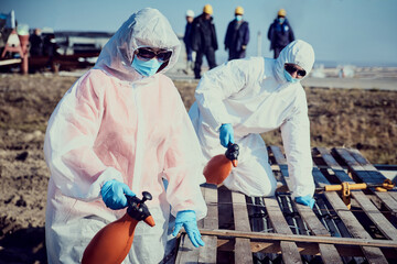 An employee in a suit, gloves, mask with equipment conducts surface sanitization
