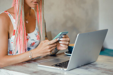 Young girl using laptop and smartphone in cafe