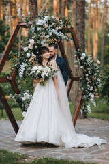 A bearded groom in a suit and a cute, beautiful brunette bride in a white dress with a long veil...