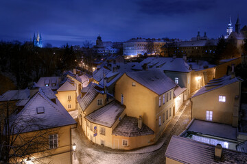 View of New World district with two streets and the house on the corner illuminated with lanterns in the winter snowy morning. Winter. Snow. Travel. Prague, Czech Republic.	
