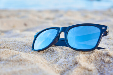 Fototapeta na wymiar Mirror sunglasses on the sand beach with sky reflection