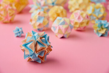 Set of multicolor handmade modular origami balls or Kusudama Isolated on pink background. Visual...