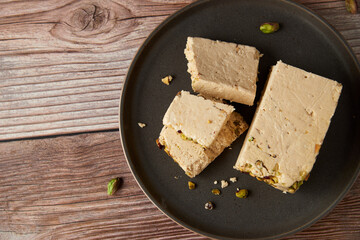 Organic halva with pistachios on a wooden surface. Traditional middle eastern sweets. Jewish, turkish, arabic oriental national dessert. Turkish delight concept. Natural vegan product. Copy space.