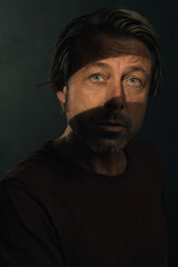 Fototapeta premium Dark mysterious portrait of a blond man with light blue eyes and