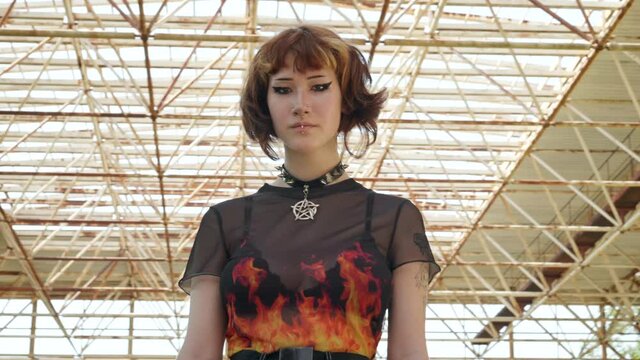 Asian teen girl looks directly camera with short haircut on wall background slide turn of an abandoned building sunny day summer. Portrait An alternative in youth. Protests. Freedom. Freak