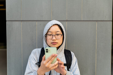 Young Asian adult using cell phone wearing glasses