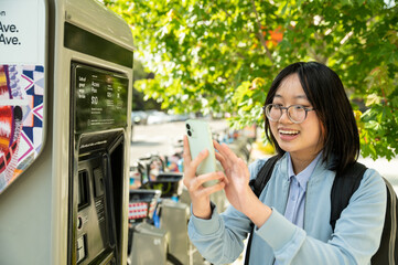 Young woman using cell phone at bike share station while commuting