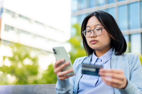 Young Asian adult using credit card to make purchase on smart phone
