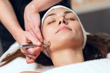 Cosmetologist making micropigmentation injection on face for rejuvenation while lying on a...