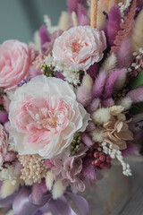 Bouquet with roses, hydrangea and a and dry lagurus. Stabilized flowers in pink color in a ceramic vase at home on the dressing table.