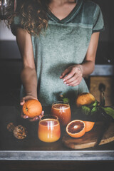 Fototapeta na wymiar Woman making fresh blood orange juice or smoothie in kitchen